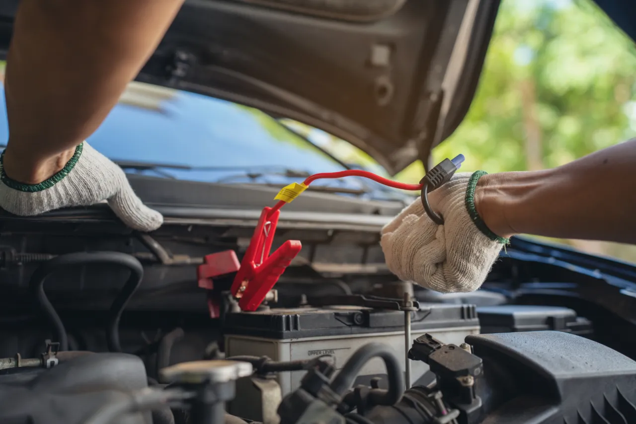 Car repair technician carrying out an emergency jumpstart of a car